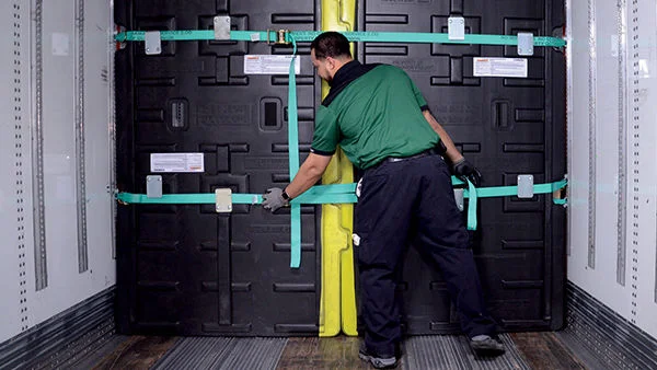 A driver securing a security divider inside a freight truck to protect and separate cargo during transport.